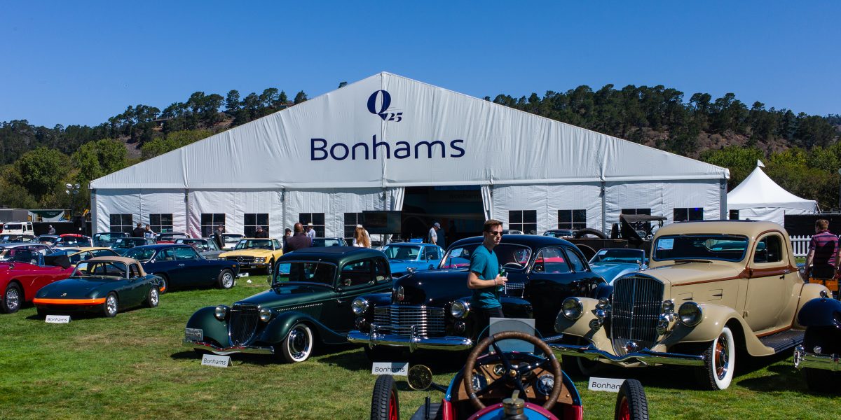 Cars on display in front of auction tent